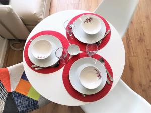 ポルトにあるAPOSENTUS - Your Home at Pinheiro's Studioの白いテーブル(赤皿、ワイングラス付)