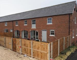 a red brick building with a wooden fence at The Barn, Wolds Way Holiday Cottages, 2 bed ground floor in Cottingham