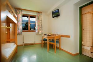 a room with a table and a bed and a desk at Junges Hotel Zell am See in Zell am See