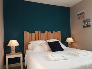 a bedroom with a large white bed with two lamps at Apartment Cap Meyran in Gujan-Mestras