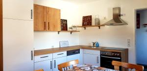 ヴェンスにあるHaus AlpenHahnの白いキャビネット、テーブルと椅子付きのキッチンが備わります。