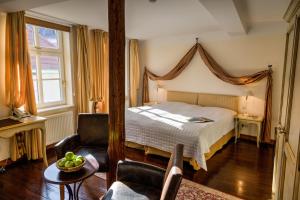 a bedroom with a bed and a chair and a table at Hotel Zum Bär in Quedlinburg