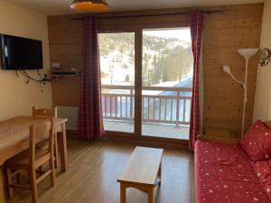 een woonkamer met een bank en een tafel en een groot raam bij Boost Your Immo Chalet des Rennes 83 in Vars