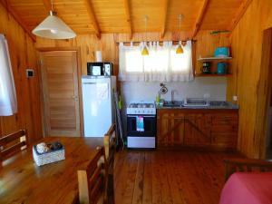 a kitchen with a table and a refrigerator and a stove at Casita de Madera in San Carlos de Bariloche