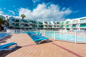 a row of lounge chairs in front of a resort at Vivienda Vacacional Namana Beach in Costa Teguise