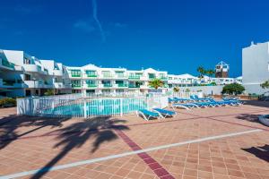 a group of blue lounge chairs in front of a resort at Vivienda Vacacional Namana Beach in Costa Teguise