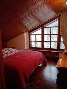 a bedroom with a red bed and a large window at Mansarda condominio Royal in Valtournenche