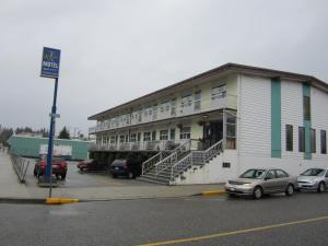 a building with cars parked in a parking lot at Aleeda Motel in Prince Rupert