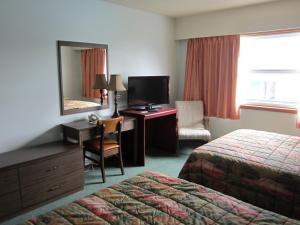 a hotel room with a bed and a desk with a mirror at Aleeda Motel in Prince Rupert +37 photos