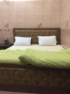 - un lit avec 2 oreillers et une couverture verte dans l'établissement Royal Residency, à New Delhi