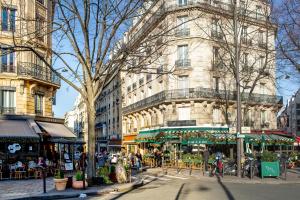 a building with tables and chairs on a city street at Hôtel Mercure Paris Centre Gare Montparnasse in Paris