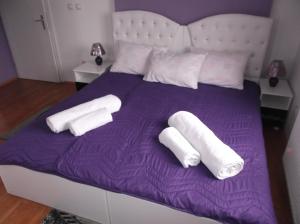 fioletowe łóżko z dwoma białymi ręcznikami w obiekcie Prenociste Bojan 017 w mieście Vranje