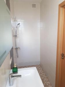 ein weißes Bad mit einer Dusche und einem Waschbecken in der Unterkunft Stylish apartment Riga in Riga
