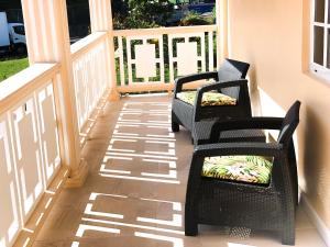 two chairs on a porch with their shadows on the floor at Calliandras Apartment Complex in Kingstown