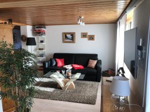 a living room with a black couch and a glass table at Ferienwohnung Milchgaessli in Frutigen