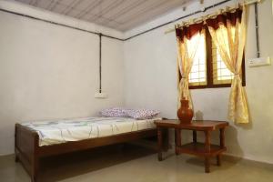 a bedroom with a bed and a table and a window at Best Kerala Homestay in Kattappana