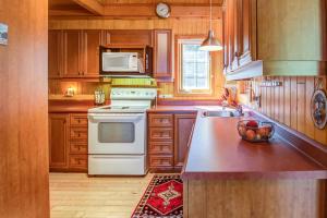 a kitchen with wooden cabinets and a white stove top oven at Le Cent in Saguenay +10 photos