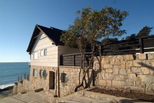 a house with a stone wall next to the ocean at Hotel Boutique Casadoca in Concón