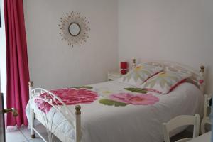 um quarto com uma cama branca com flores cor-de-rosa em Gîte **** "le refuge des fées" em Saint-Julien-du-Gua