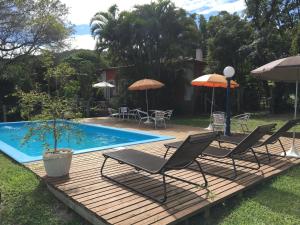 una terrazza con sedie e ombrelloni accanto alla piscina di Pousada Villa Agrifoglio a Praia do Rosa