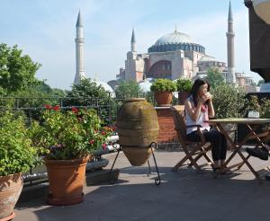 una mujer sentada en una mesa frente a una mezquita en Hotel Uyan-Special Category, en Estambul