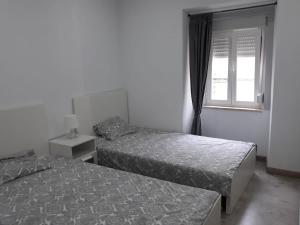 two beds in a room with a window at Chainha's Dream Apartment in Sesimbra +8 photos