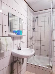 a white bathroom with a sink and a shower at Hotel & Restaurant Gulfhof in Emden