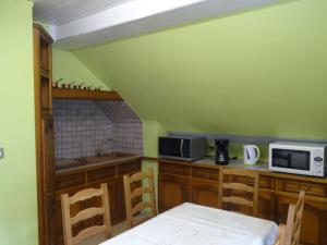 a kitchen with green walls and wooden cabinets at Gîte Henry in Orbey