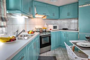 a kitchen with blue cabinets and a sink and a table at Holiday House Ioanna in Nea Peramos