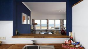 a kitchen with blue walls and a sink and a table at Apartment Valdemosa in De Haan