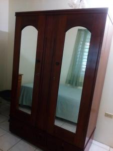 a wooden dresser with two mirrors in a room at Cozy & Comfy in Portmore