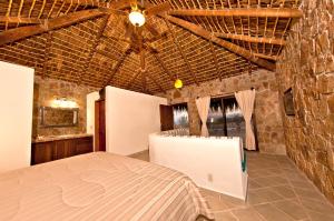 a bedroom with a bed and a stone wall at Palapas La Choya in La Ventana