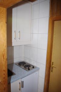 a small kitchen with a stove and white cabinets at Ferienhaus Forellenwirt in Grünbach +9 photos