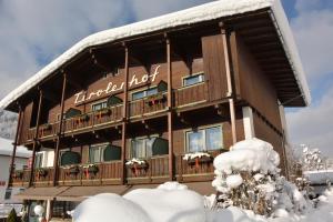 duży drewniany budynek z balkonem w śniegu w obiekcie Hotel Garni Tirolerhof w mieście Hopfgarten im Brixental