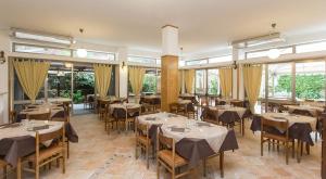 a dining room with tables and chairs and windows at Hotel Anna in Terracina
