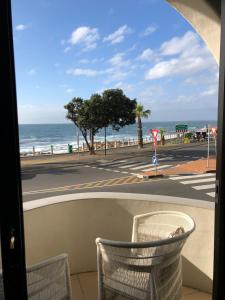 a view of the ocean from a balcony with a chair at Prince Edward Mansions in Cape Town
