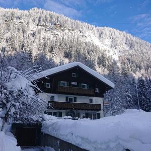 a building in the snow with a mountain at Haus am Rain in Partenen