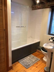 a bathroom with a tub and a toilet and a sink at Quince Cottage in Potter Heigham