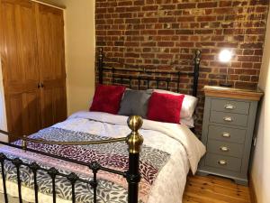 a bedroom with a bed and a brick wall at Quince Cottage in Potter Heigham