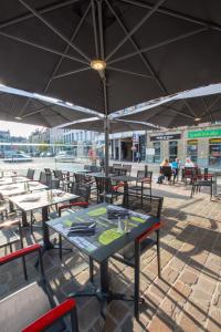 a table and chairs with umbrellas on a patio at Hôtel Les Frangins in Saint-Omer