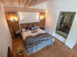 a man and woman sitting on a bed in a bedroom at Le Mirabeau Resort & Spa in Zermatt