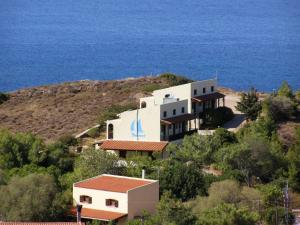 Ein Haus auf einem Hügel mit dem Meer im Hintergrund in der Unterkunft MARVINA in Volissos