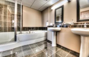 a bathroom with two sinks and a bath tub and a sink at Grand Inn & Residence- Grande Prairie in Grande Prairie +6 photos