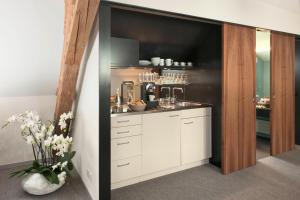 a kitchen with white cabinets and a counter with flowers at Limmathof Baden - Historisches Haus & Spa in Baden