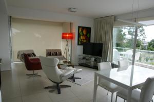 een woonkamer met een tafel en stoelen en een televisie bij Rinconada del Mar in Punta del Este