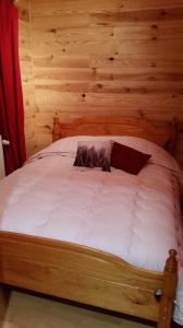 een bed in een kamer met een houten muur bij Chalet des Bruyères in La Bresse