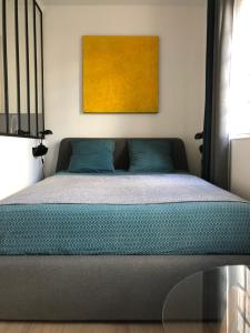1 dormitorio con 1 cama con una pintura amarilla en la pared en Deauville centre, plage, casino et hippodrome, en Deauville