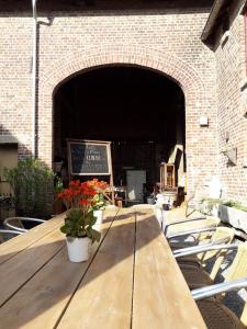 una mesa de madera con flores en la parte superior de un edificio en Een vleugje wellness in de Voerstreek - Bed & Brocante Onder de Poort en Voeren