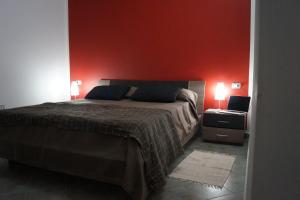 a bedroom with a bed and a red wall at Sa Domo de Mannoi in Orosei