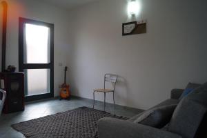 sala de estar con sofá, silla y guitarra en Sa Domo de Mannoi, en Orosei